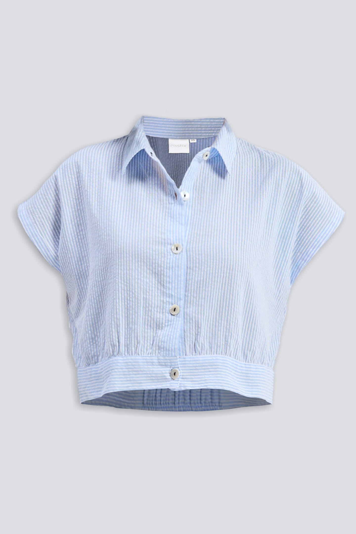 A studio product shot of the Reistor Oversized Crop Shirt in Classic Stripes, a light blue and white vertical striped button-down featuring a boxy silhouette, short cap sleeves, and a distinctive elasticated waist hem.