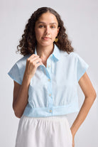 Model wearing the reistor Oversized Crop Shirt in Summer Blue, a short-sleeve organic cotton button-up with a relaxed cropped fit.