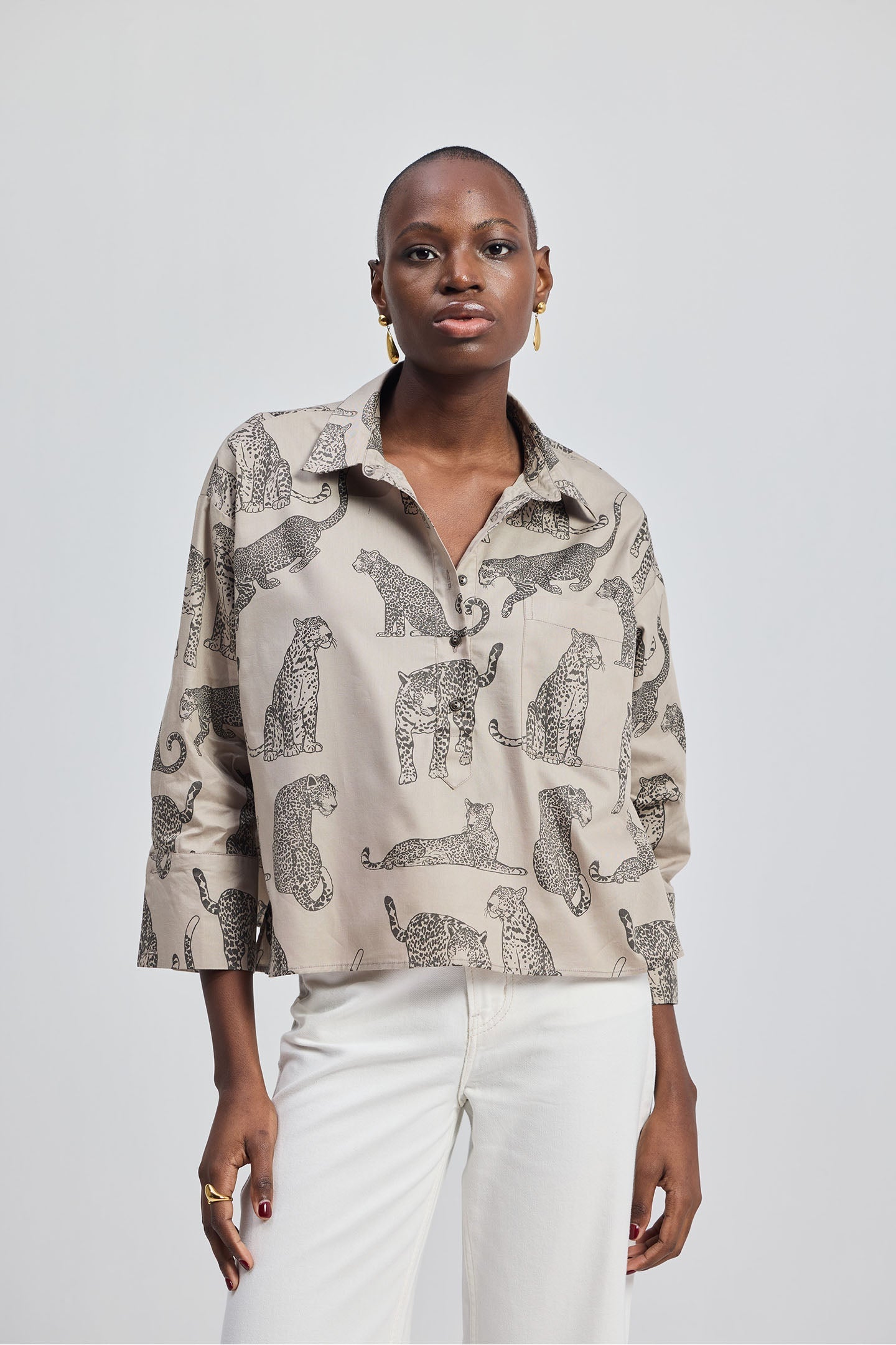 Woman wearing a patterned shirt with animal designs by reistor on a plain background.