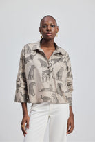 Woman wearing a patterned shirt with animal designs by reistor on a plain background.