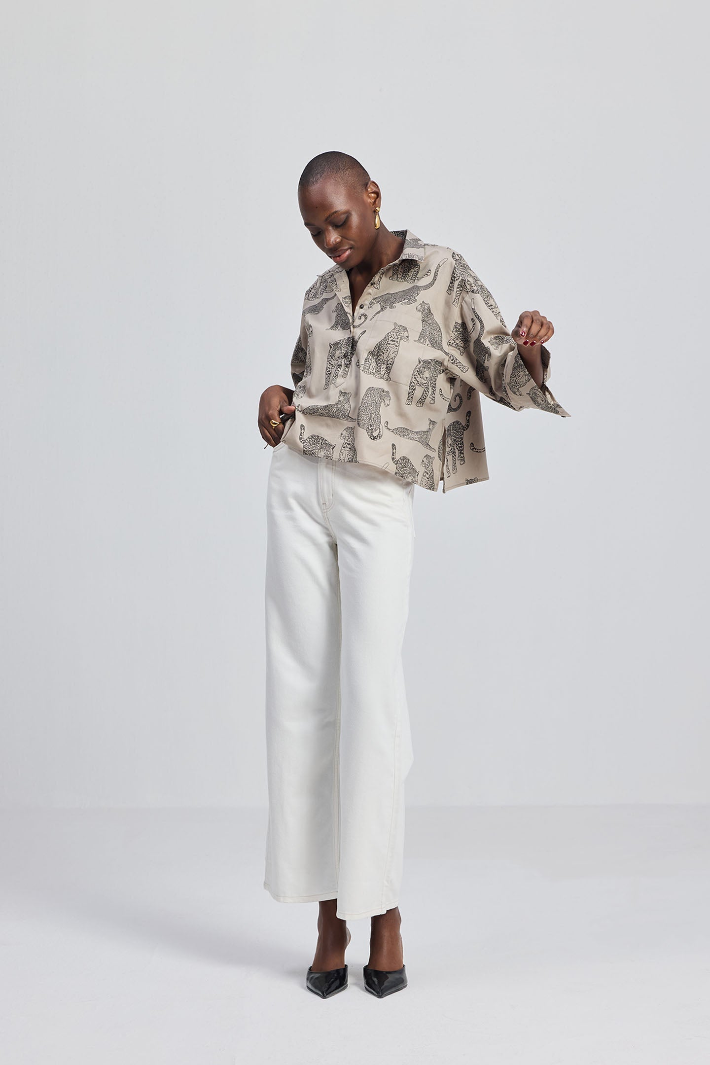 Model wearing a Reistor Oversized Cropped Button-down Shirt In Animal Print paired with white wide-leg trousers and black pointed heels.