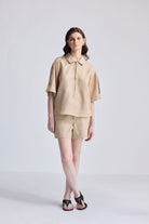 Woman wearing Oversized Flowy Shirt in Neutral Beige by reistor on white background