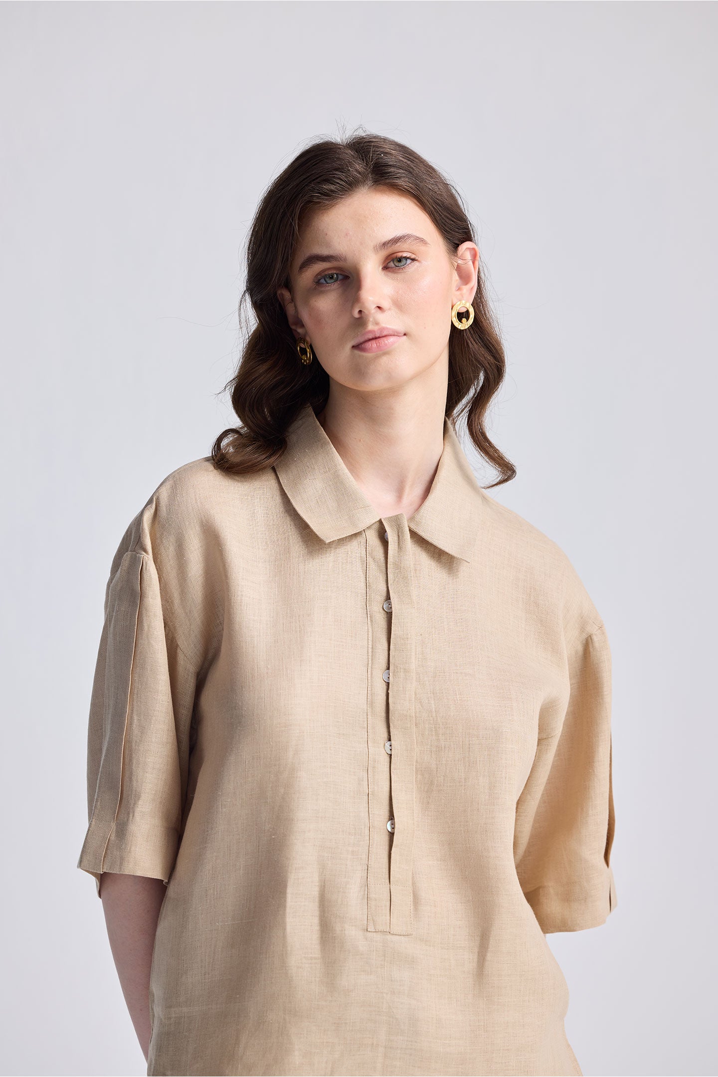 Woman wearing an Oversized Flowy Shirt in Neutral Beige, featuring a relaxed linen-look fabric, short sleeves, and a half-button placket.