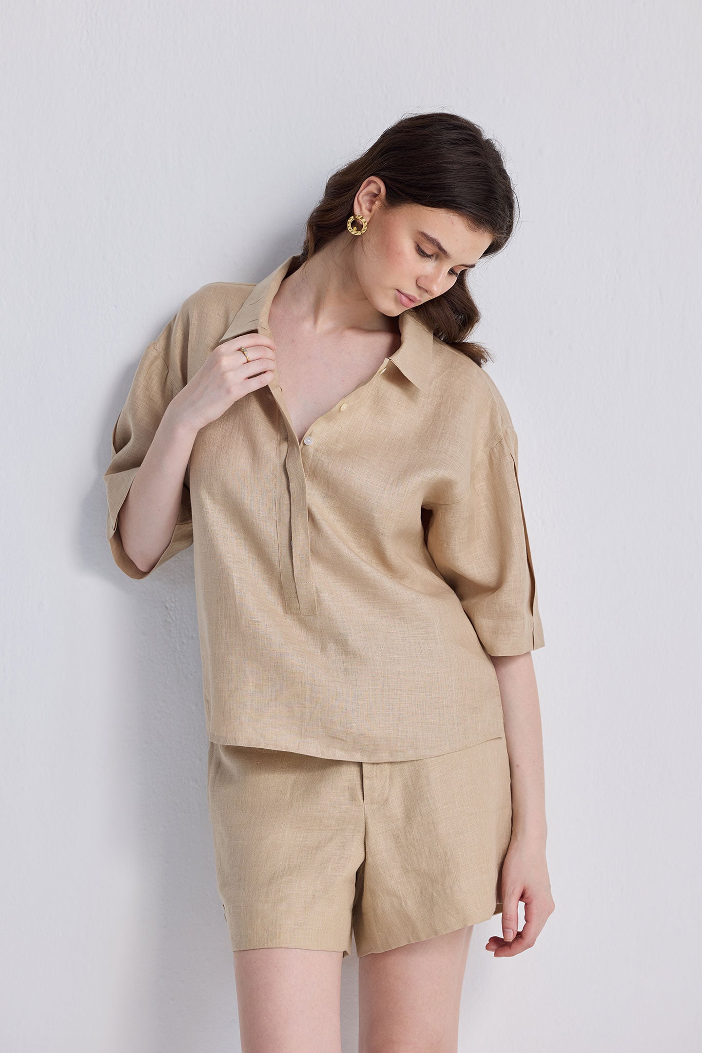 Woman modeling the Oversized Flowy Shirt in Neutral Beige, a short-sleeve linen-blend top with a relaxed fit, classic collar, and button-down front.