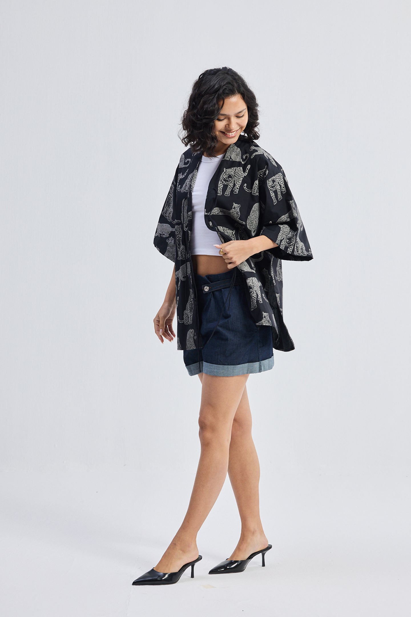 Model wearing the reistor Oversized Shirt with Front-ties in Animal Print, styled with a white crop top and denim skirt against a plain light background.