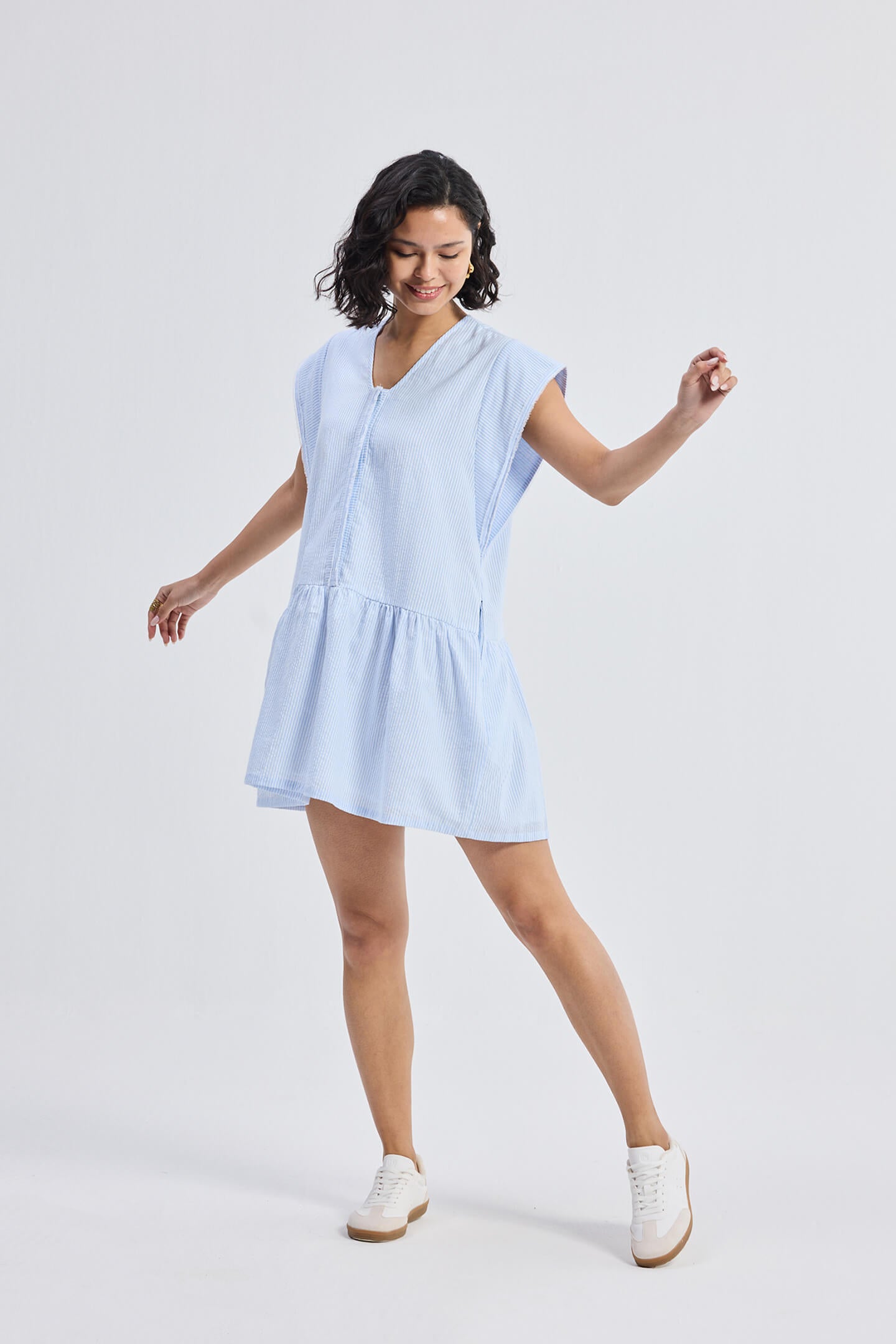  Reistor Oversized V-Neck Short Dress with Frayed Sleeves in light blue striped fabric, relaxed fit women’s summer dress styled with white sneakers and free-flowing hem.
