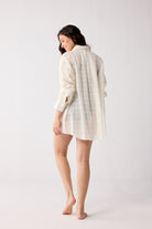 Woman wearing a white checkered shirt against a plain background