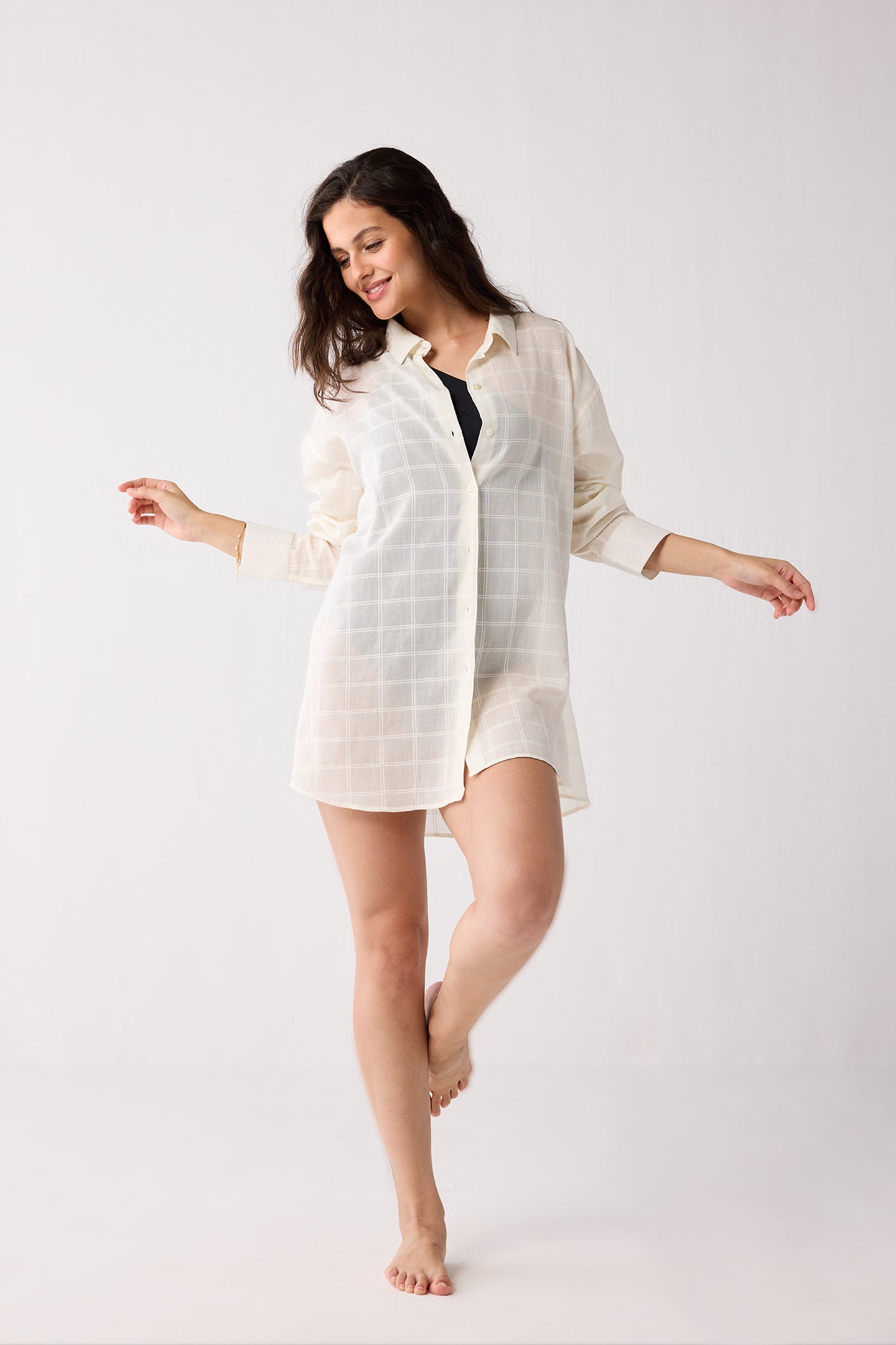 Woman wearing a white shirt over a black top on a white background