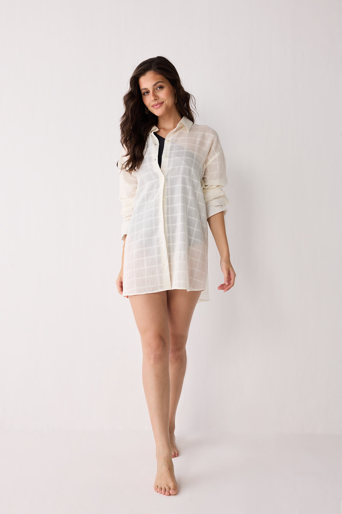 Woman wearing a white checkered shirt over a black top on a white background