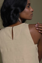 Woman wearing a Reistor beige sleeveless top with a cutout detail on a plain background.