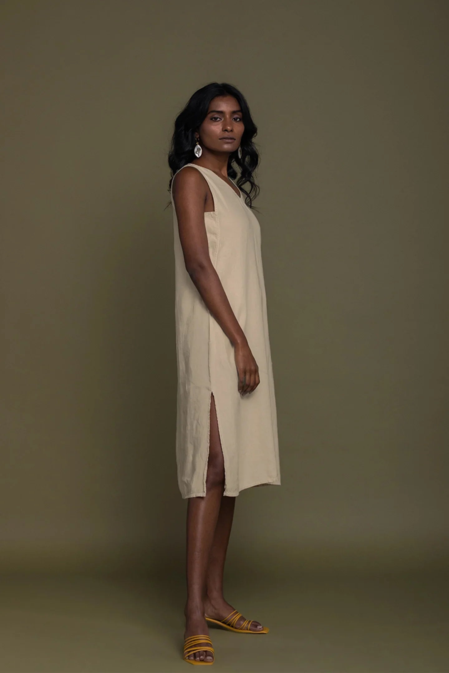 Side view of Reistor Reading Tea Leaves Dress in Neutral Beige, sleeveless V-neck midi dress with side slit.