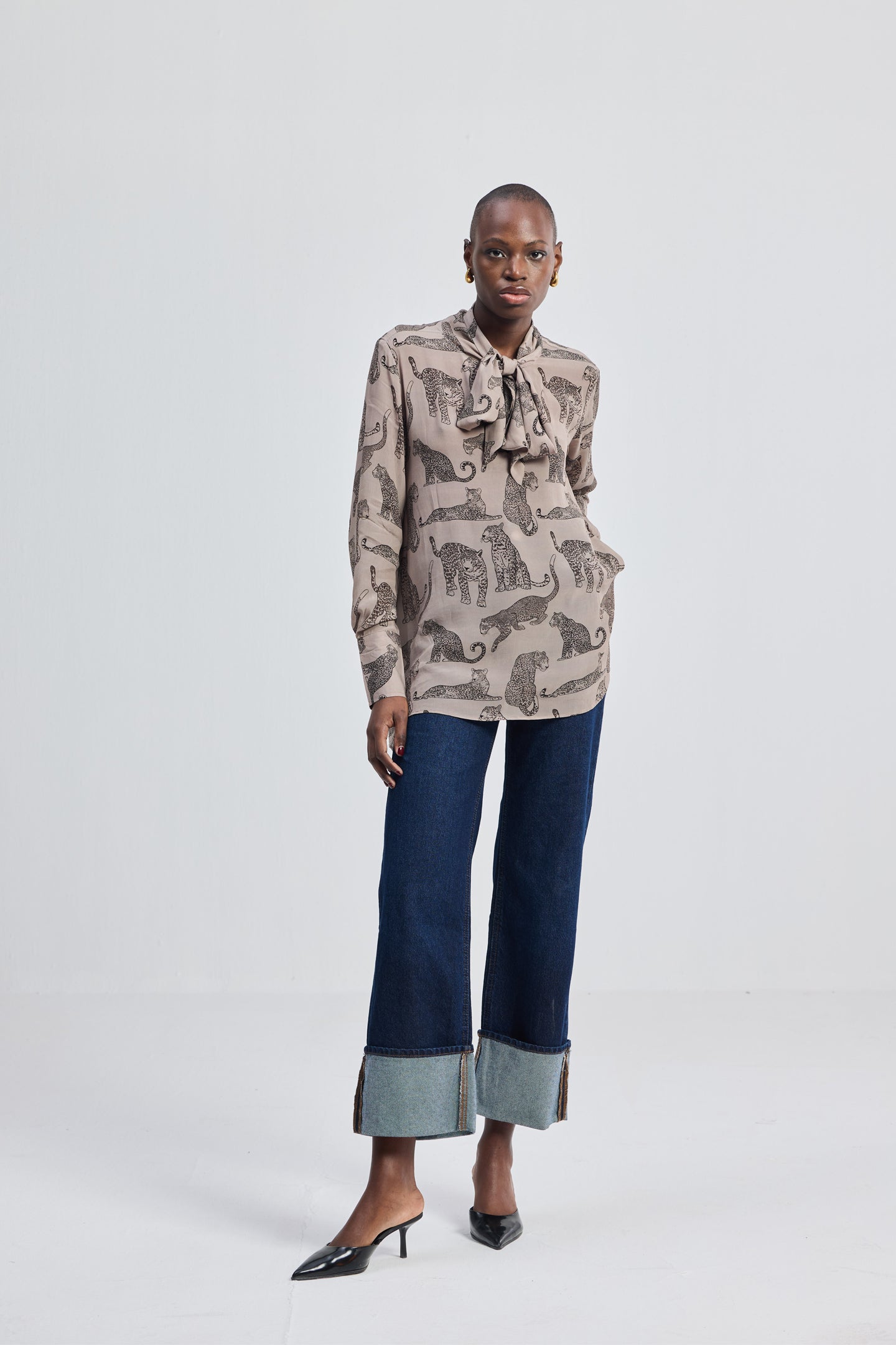Reistor Relaxed-Fit Top with Front-tie in Animal Print, full-body front view featuring long sleeves, tie-neck detail, animal print pattern, and a relaxed fit styled with wide-leg denim and heels.
