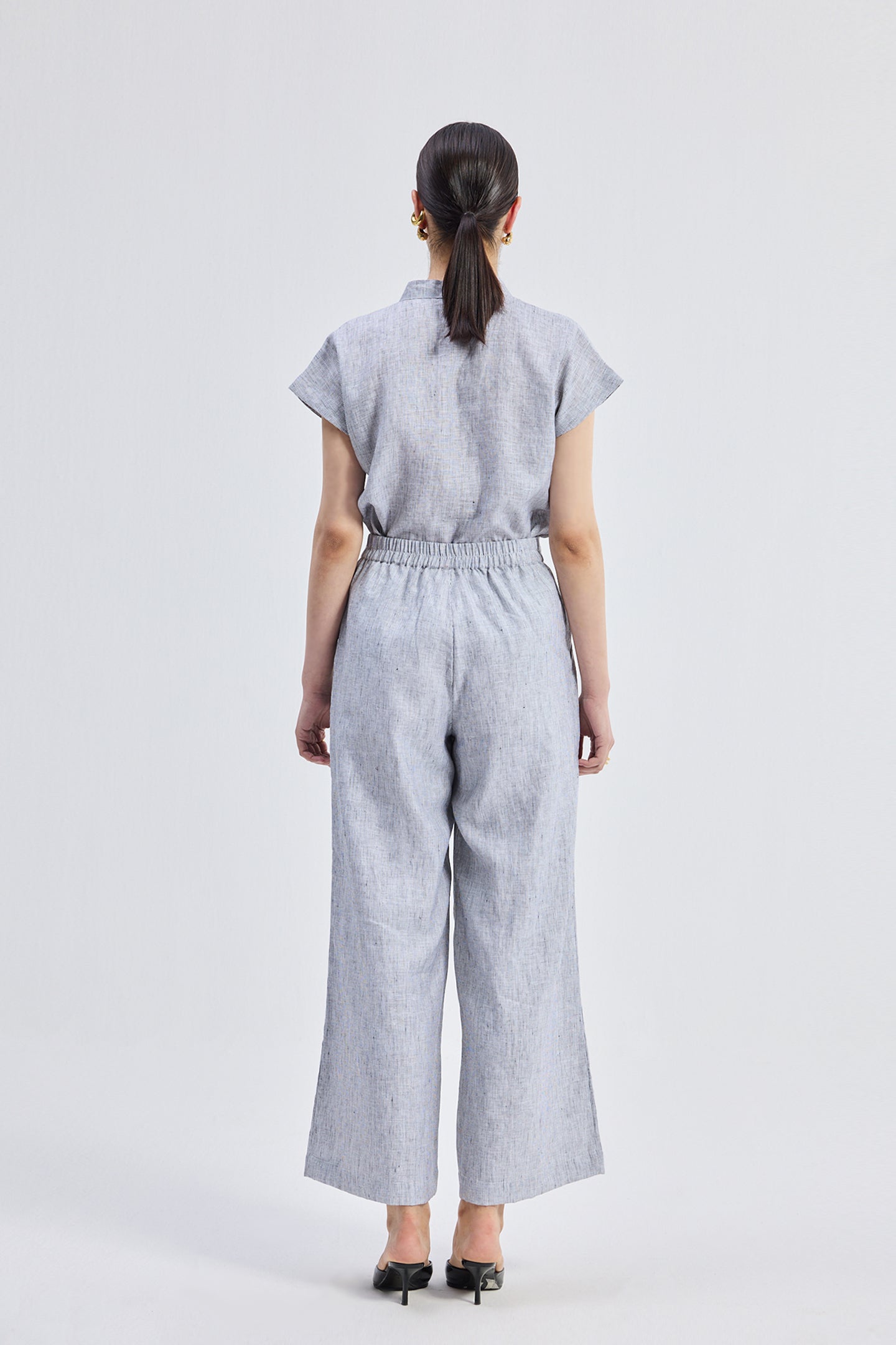 Back view of the Relaxed-fit Shirt Set in Linen Stripes by Reistor, showcasing the breathable striped linen fabric, relaxed silhouette, and matching wide-leg pants in a sustainable design.