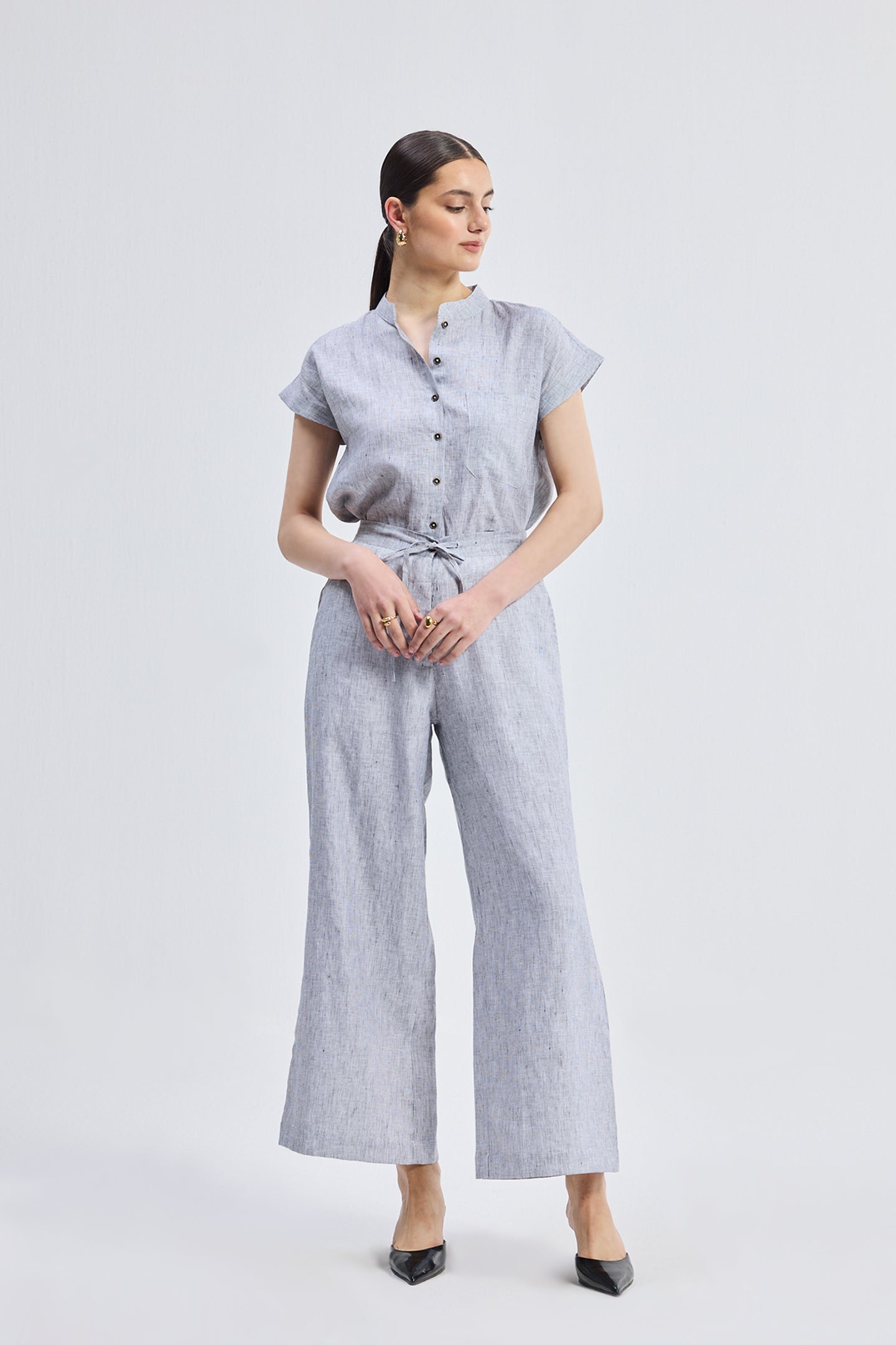 Front view of a model wearing the Relaxed-fit Shirt Set in Linen Stripes by reistor, featuring a light blue and white pinstriped short-sleeve button-down shirt tucked into matching wide-leg linen trousers with a drawstring waist.