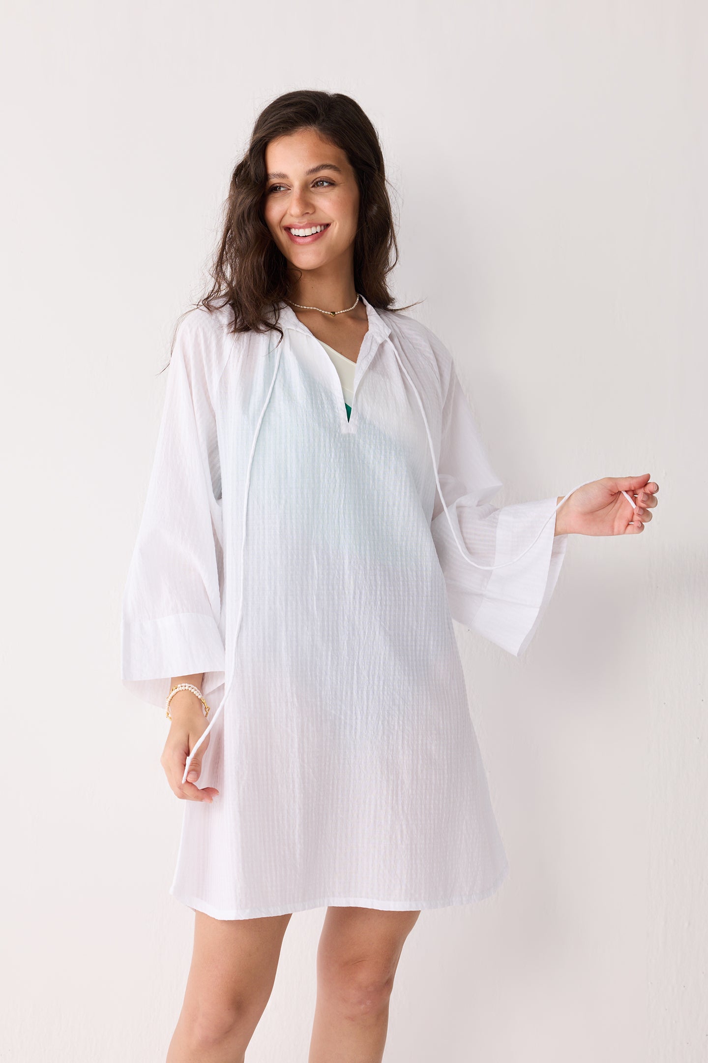 A woman wearing a white cover-up with a plain background