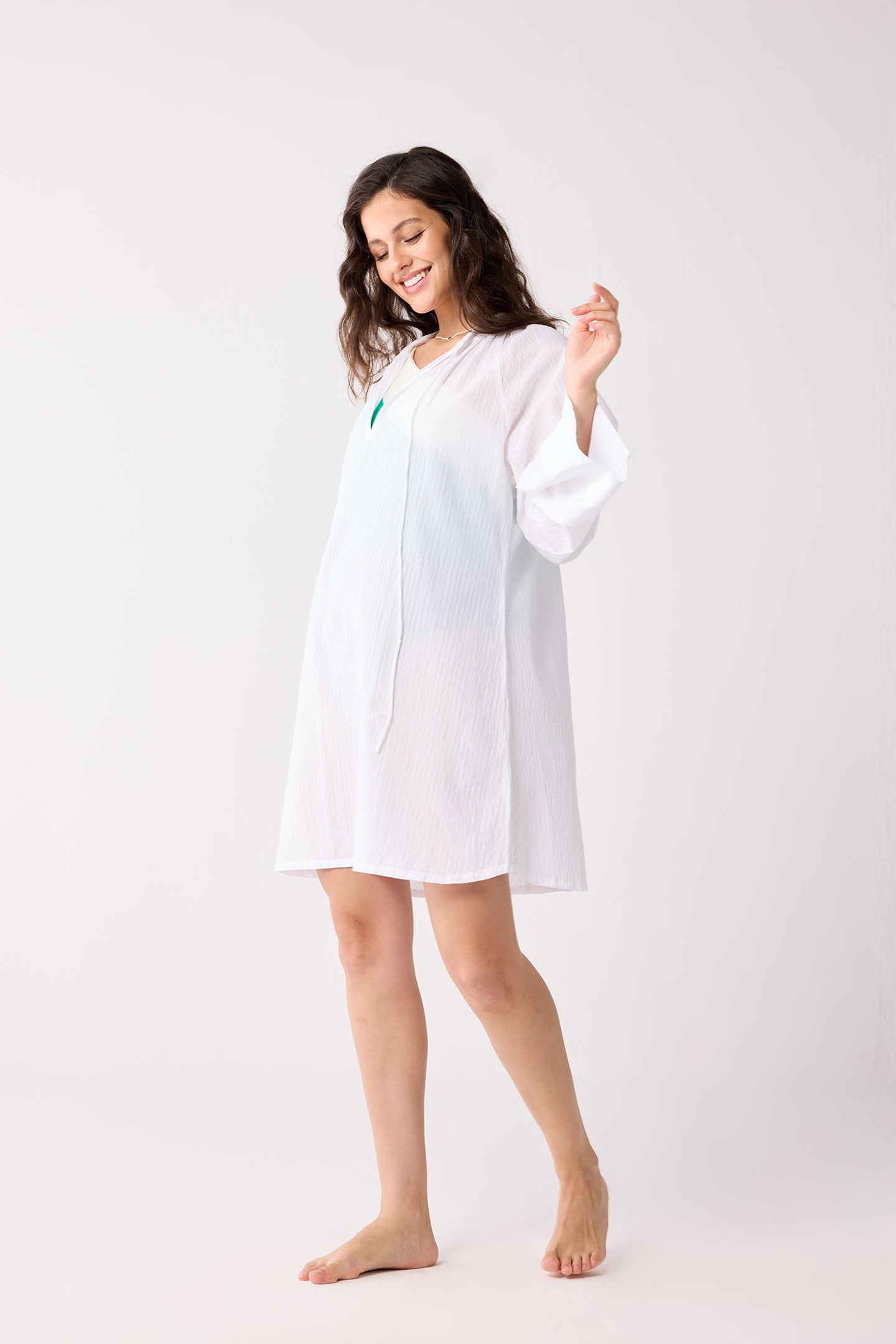 Woman wearing a white beach cover-up against a white background