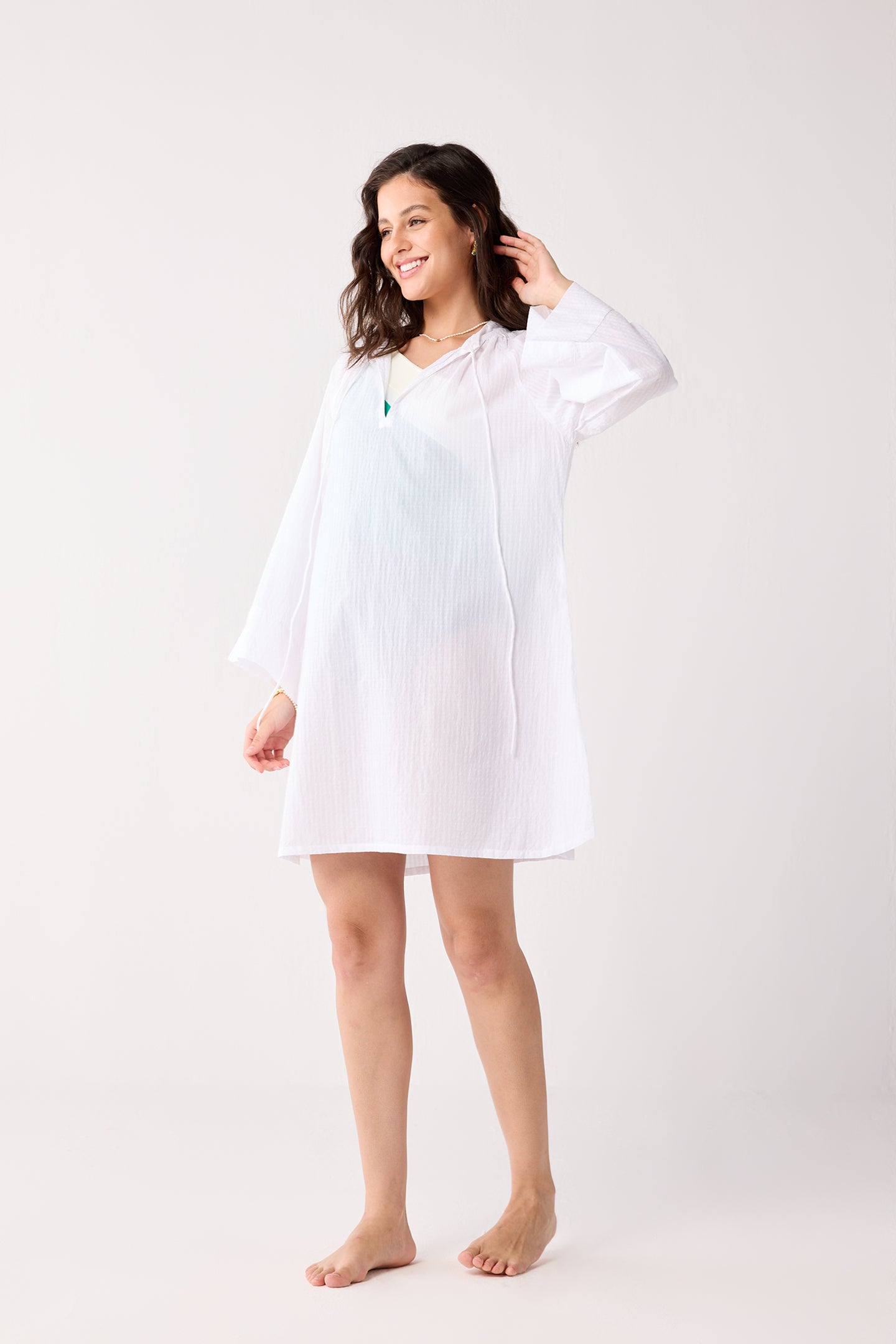 Woman wearing a white cover-up against a white background