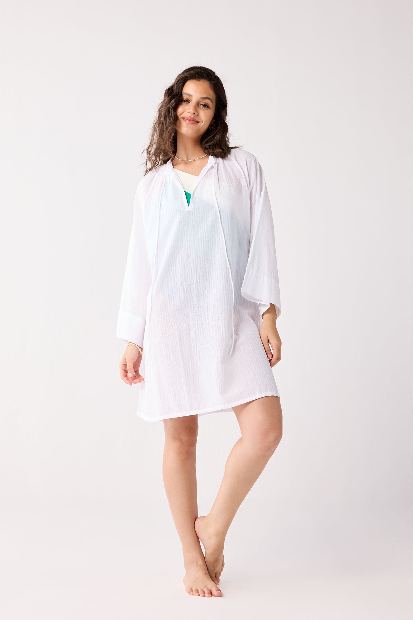 Woman wearing a white cover-up with a matching cardigan on a white background