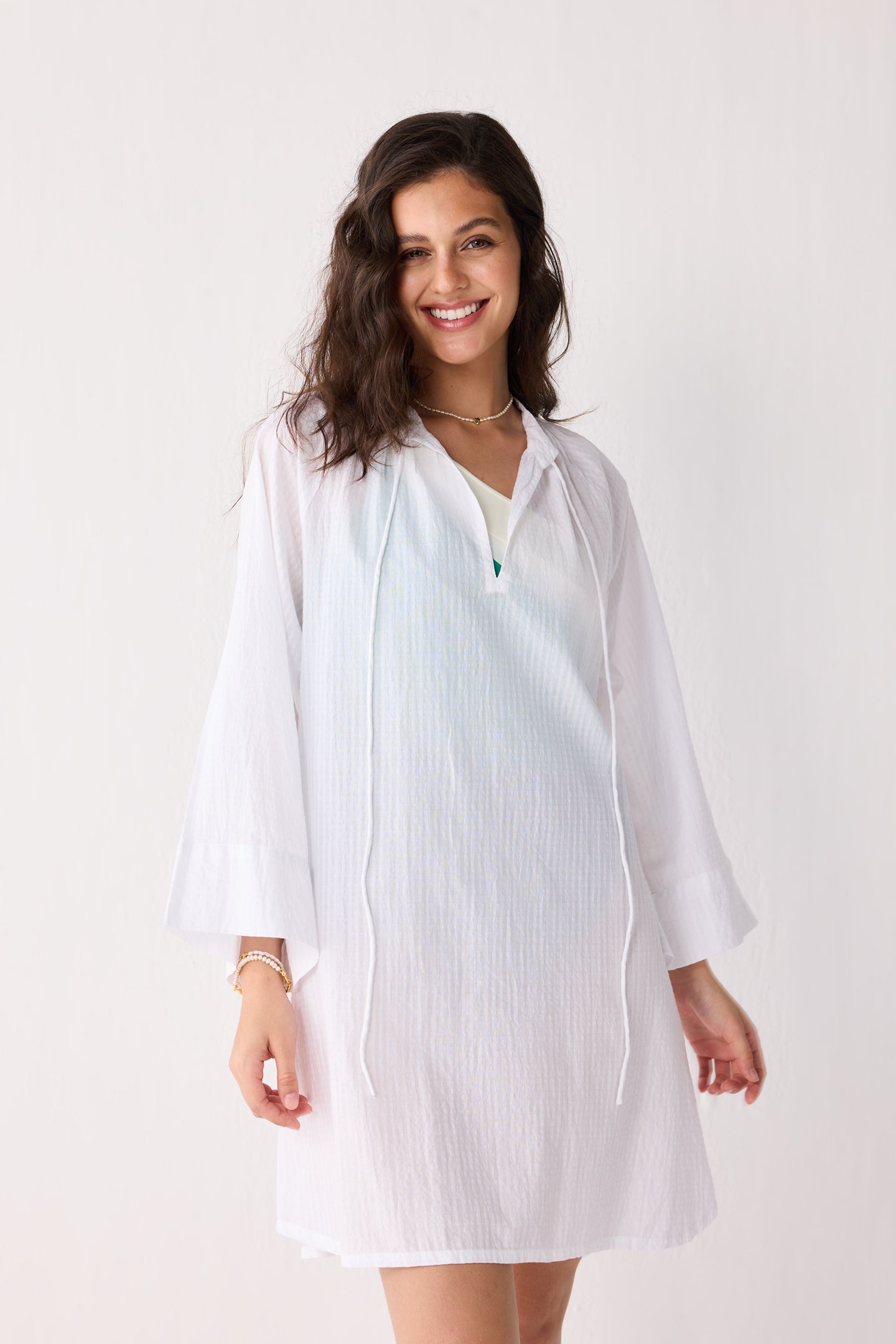 Woman wearing a white cover-up on a plain background