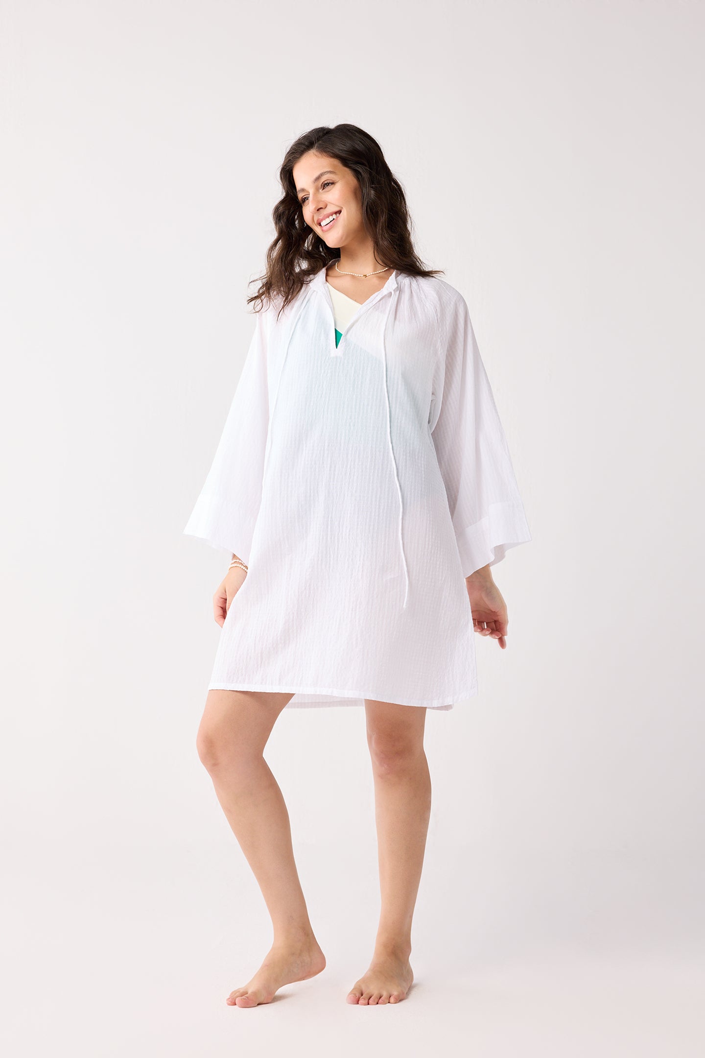 Woman wearing a white cover-up on a plain background