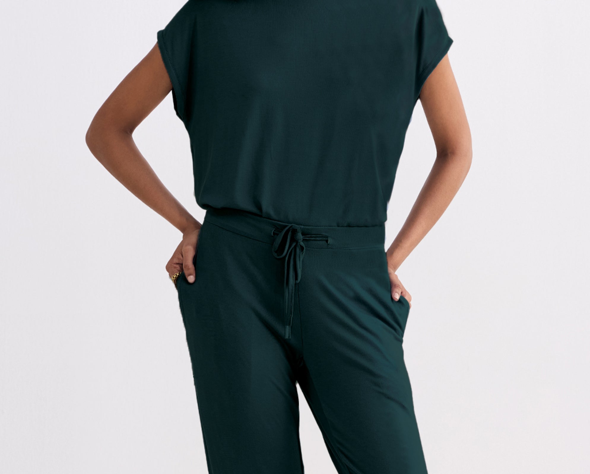 Person wearing a Teal jumpsuit on a light gray background