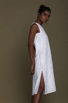 white beach dress with embroidered details all over. The dress is knee length with side slits.