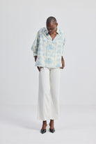 Front view of a model wearing the reistor Relaxed-fit Shirt with Drawstring in Animal Print, styled with white wide-leg pants and heels on a clean studio background.
