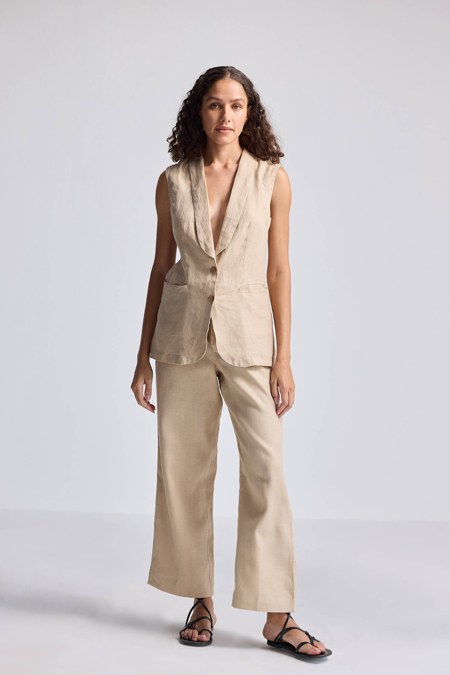 Model wearing the reistor Sleeveless Hemp Jacket in a neutral beige tone, styled with matching wide-leg pants and sandals for a minimal, sustainable fashion look.