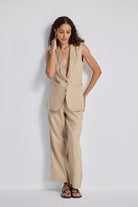 Model styling Reistor Sleeveless Hemp Jacket Set in natural beige, featuring a sleeveless tailored hemp jacket with button detail paired with wide-leg hemp trousers, showcasing sustainable women’s fashion.