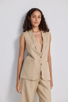 Close-up front view of model wearing Reistor Sleeveless Hemp Jacket Set in natural beige, highlighting the sleeveless tailored hemp jacket with notch lapel, button closure, and eco-friendly fabric for sustainable women’s fashion.