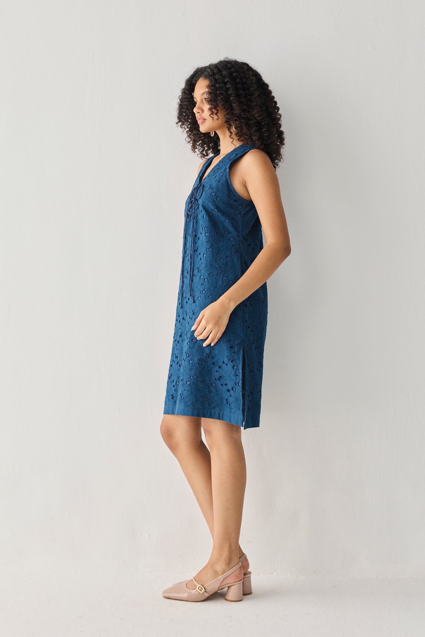 Sleeveless Knee-Length Dress in Blue featuring an all-over embroidered eyelet pattern, V-neckline, and relaxed straight silhouette, shown from the side in a full-length studio portrait with a lightweight, easy-to-wear design.