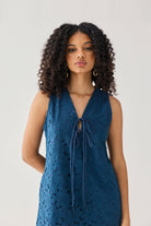 Sleeveless Knee-Length Dress in Blue featuring intricate all-over eyelet embroidery, a V-neckline with delicate self-tie detailing, and a flattering sleeveless silhouette, shown from the front in a studio portrait highlighting the textured fabric and elegant design.