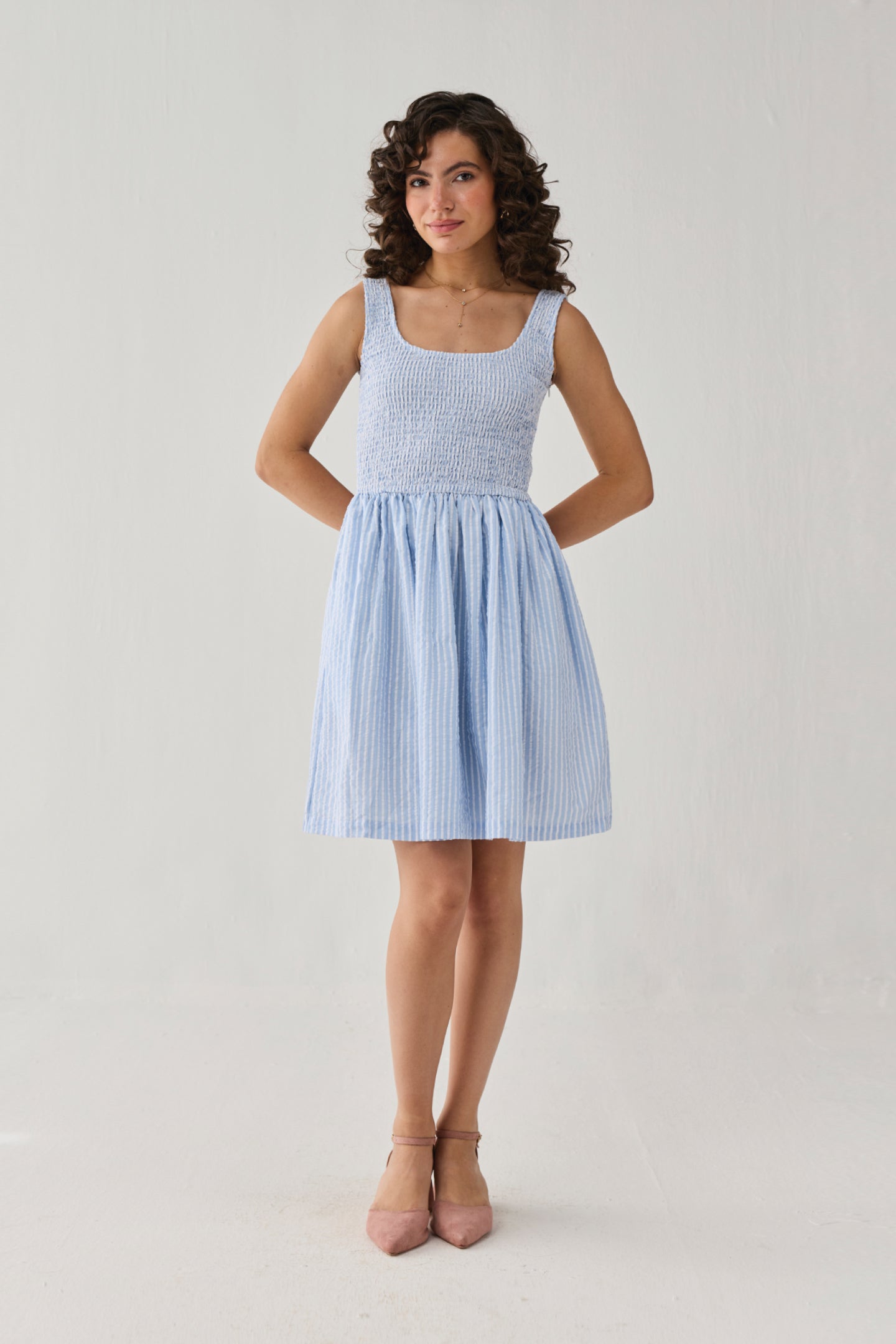 Sleeveless blue stripe mini dress featuring a textured smocked top, flattering fit-and-flare silhouette, and airy design for warm days.