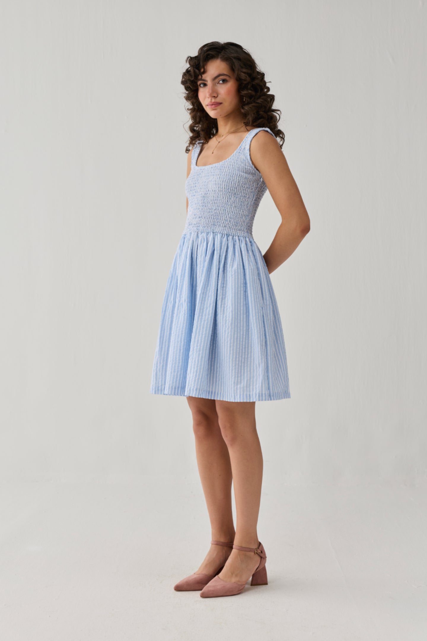 Light blue striped smocked short dress featuring a textured bodice and airy skirt, creating a fresh and graceful daytime look.