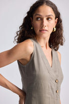 Close-up of model wearing the Straight Dress with Front Slit in Dark Green Hemp by reistor, highlighting the sleeveless V-neck design, wooden buttons, and textured hemp fabric.