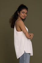 Side view of The Endless Sunday Top in White by Reistor, featuring a relaxed sleeveless silhouette, breathable fabric, curved hem, and effortless everyday style.