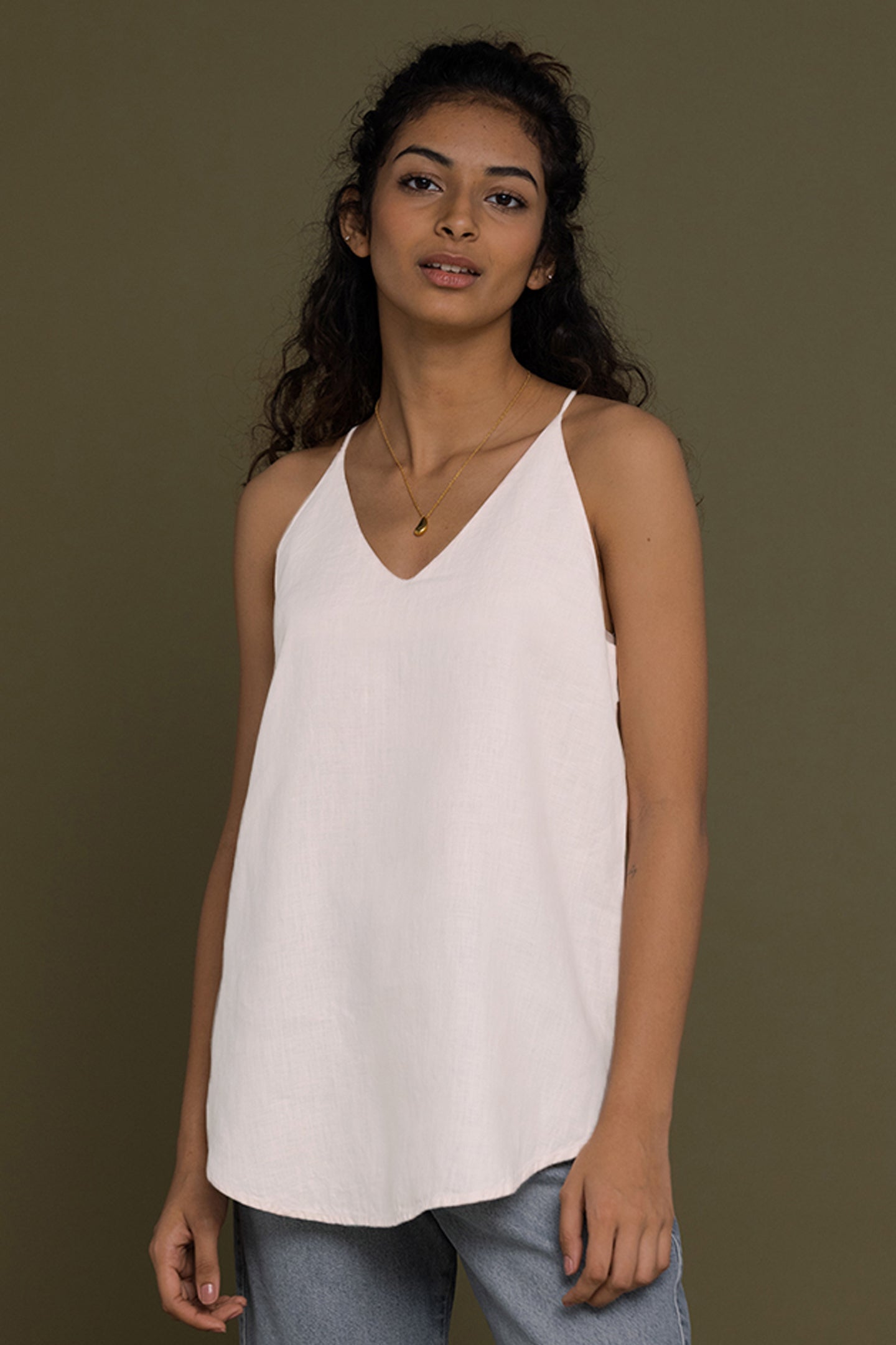 The Endless Sunday Top in White by Reistor, a minimalist sleeveless women's top with a relaxed fit, breathable fabric, elegant V-neck, and versatile everyday style.