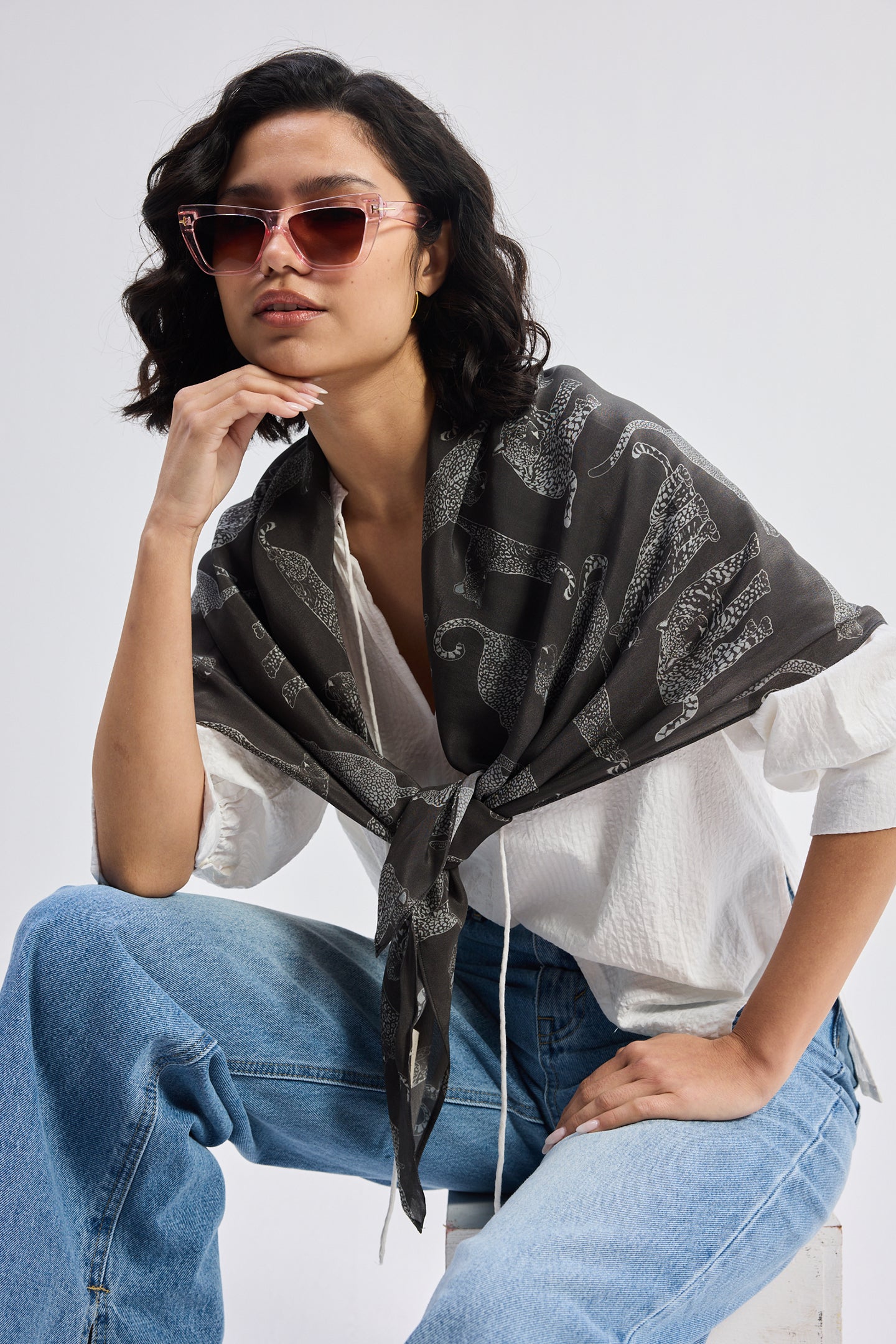The Mara Scarf in Black over a white top with blue denim jeans.