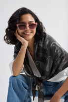 Close-up lifestyle shot of The Mara Scarf in Black styled over a white top with jeans.