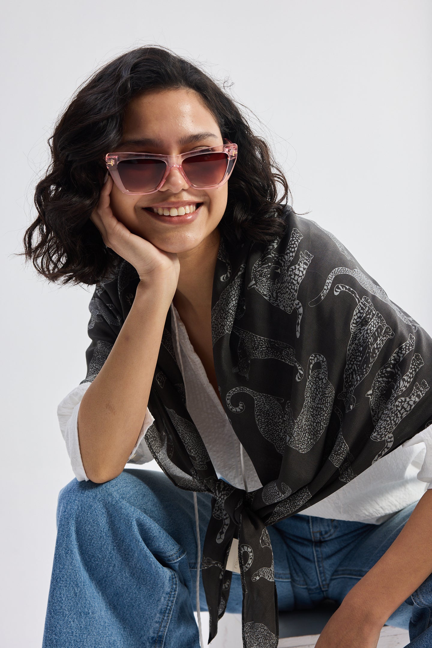 Close-up lifestyle shot of The Mara Scarf in Black styled over a white top with jeans.