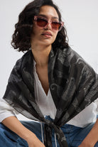 The Mara Scarf in Black styled casually with a white top and denim.