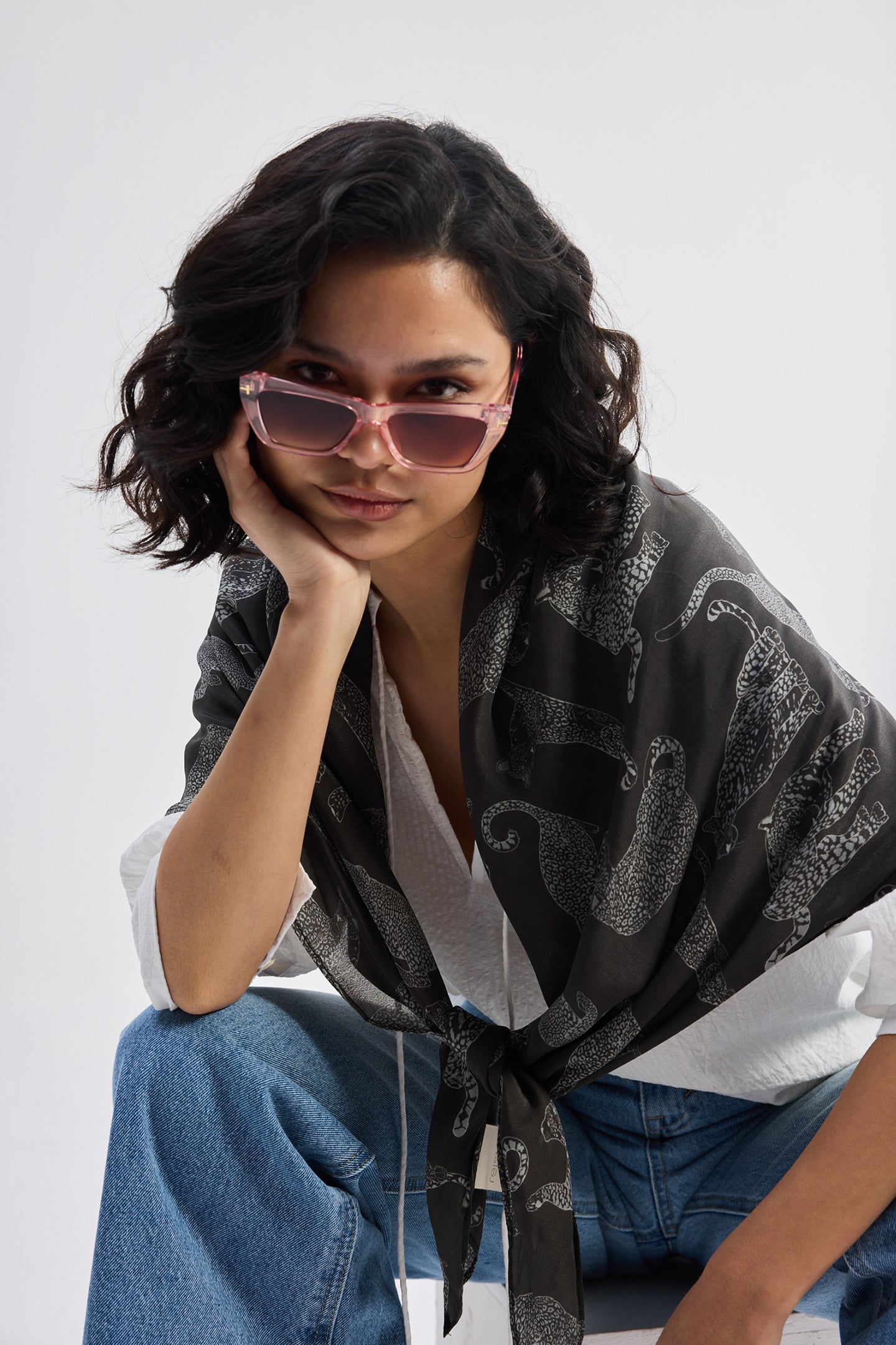 The Mara Scarf in Black styled in a relaxed knot with a white top and blue denim.