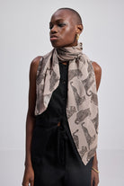 The Mara Scarf in Brown styled on a model with a black outfit, featuring a soft animal print and draped knot detail.