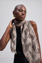 The Mara Scarf in Brown draped on model with leopard print pattern