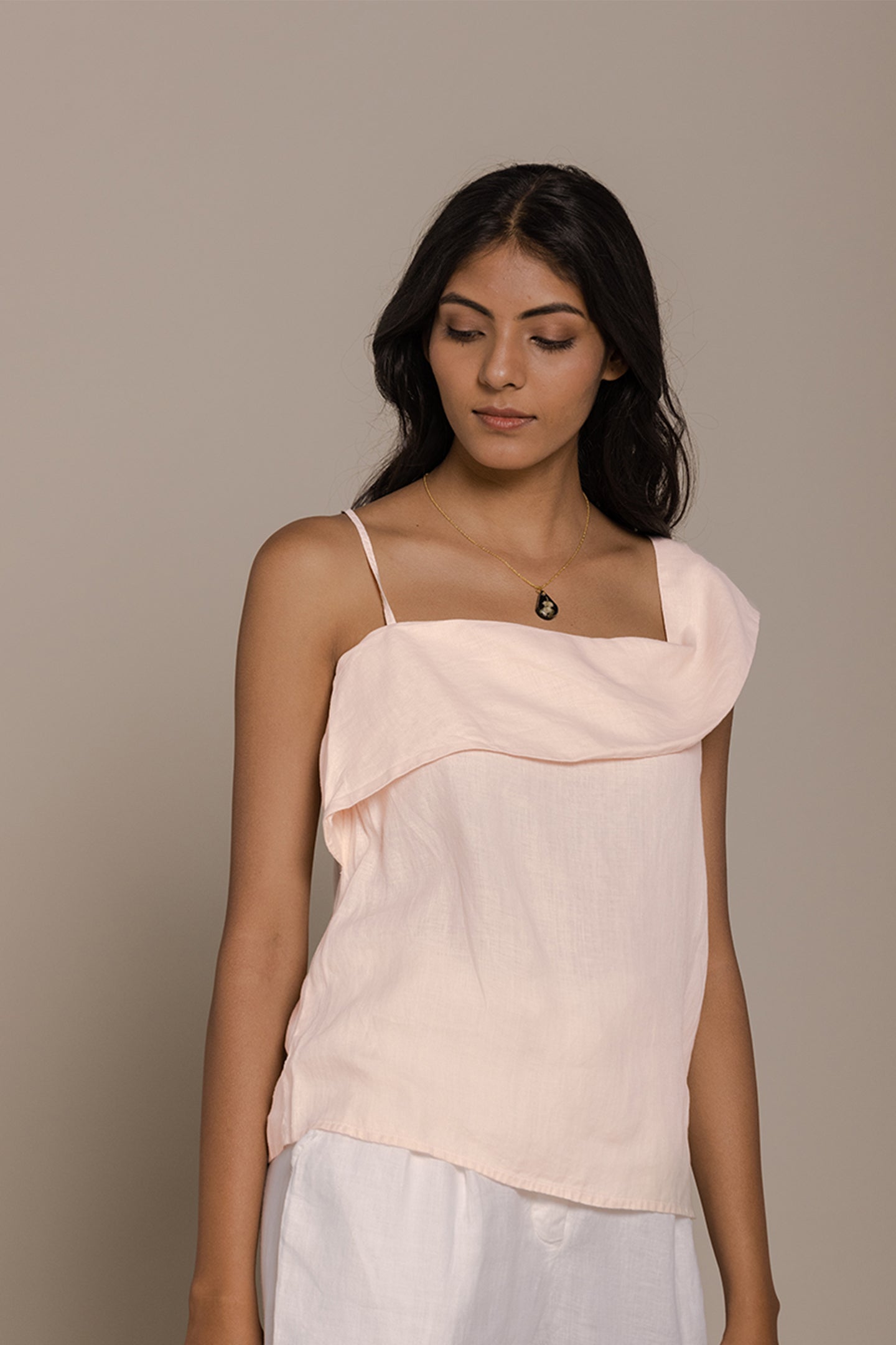 A woman wearing an ice pink one-shoulder flat strap top with a flattering neckline.