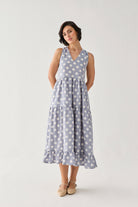 Tiered Midi Dress in Blue Polka with a relaxed empire-waist silhouette, oversized white dots, and a softly ruffled hem, styled in a graceful head-tilt pose.