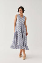 Tiered Midi Dress in Blue Polka with oversized white dots, a sleeveless V-neck bodice, and a swaying layered skirt, captured mid-step to showcase its fluid movement.