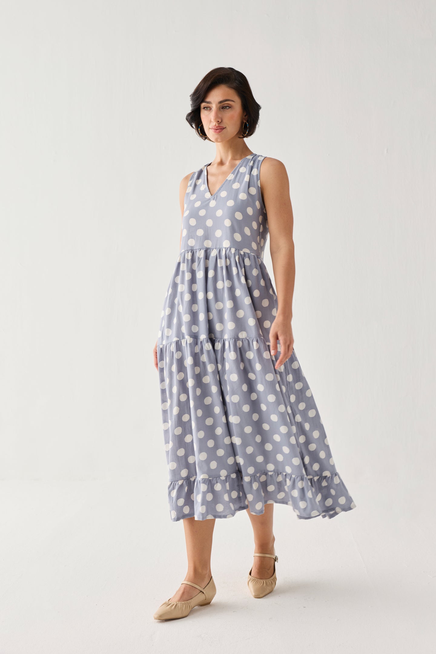 Tiered Midi Dress in Blue Polka featuring a breezy sleeveless silhouette, oversized dot print, and fluttering ruffle hem, captured in motion for a graceful look.