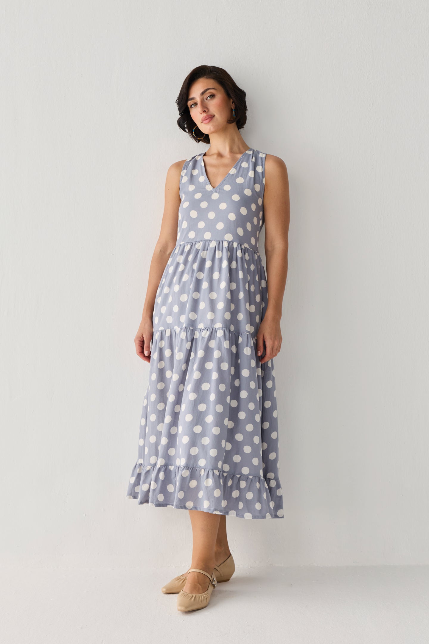 Blue Polka Tiered Midi Dress with a flowing three-tier skirt and flattering V-neckline, styled in a graceful pose that highlights its drape.