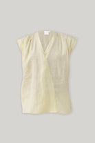 Flat lay of Reistor's V-neck Overlap Top in Butter Lemon, showcasing its elegant overlap neckline, cap sleeves, and relaxed silhouette.